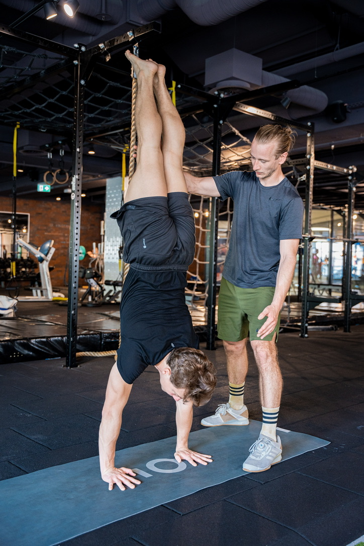 Dominic Kutschki sichert einen Klienten im Handstand während einer Trainingseinheit.